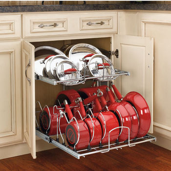 An open kitchen drawer holding red pots and pans.
